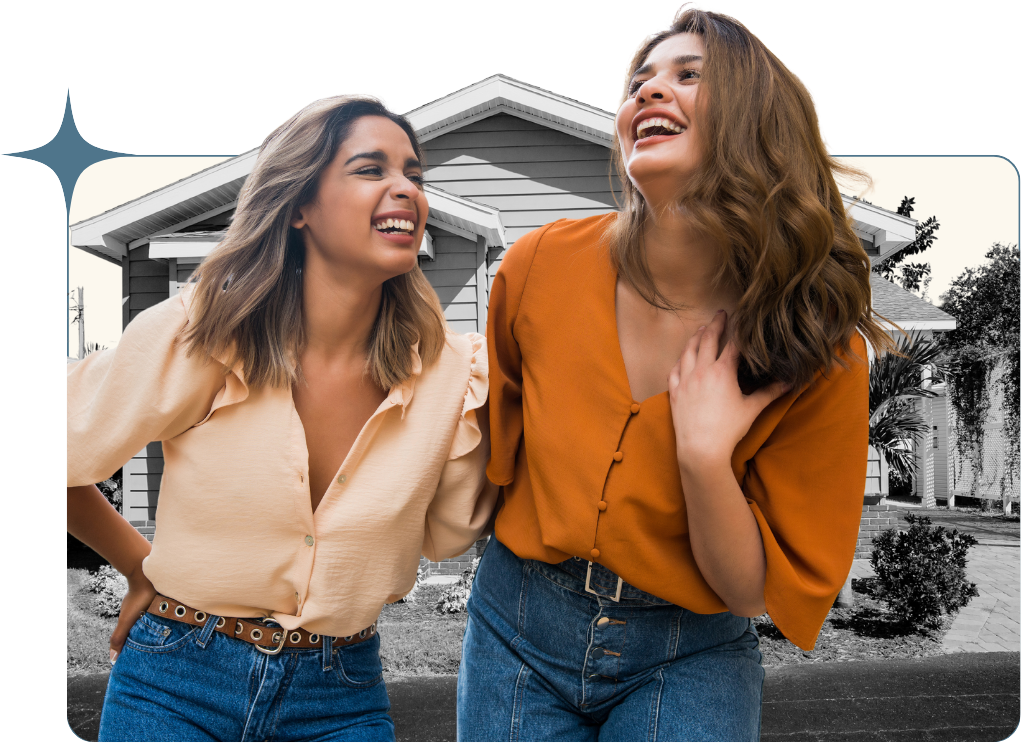 Two women laughing in front of a tiny home.